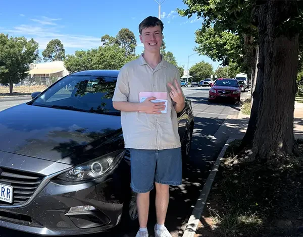 Newly licensed driver beside a dual-control training vehicle